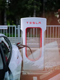 Tesla Model 3 beim Laden an Ladestation mit rot-weißem Schild