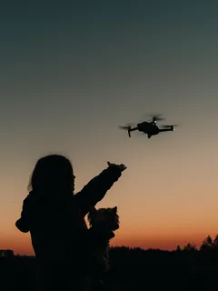 Person steuert ferngesteuerten Hubschrauber bei Sonnenuntergang